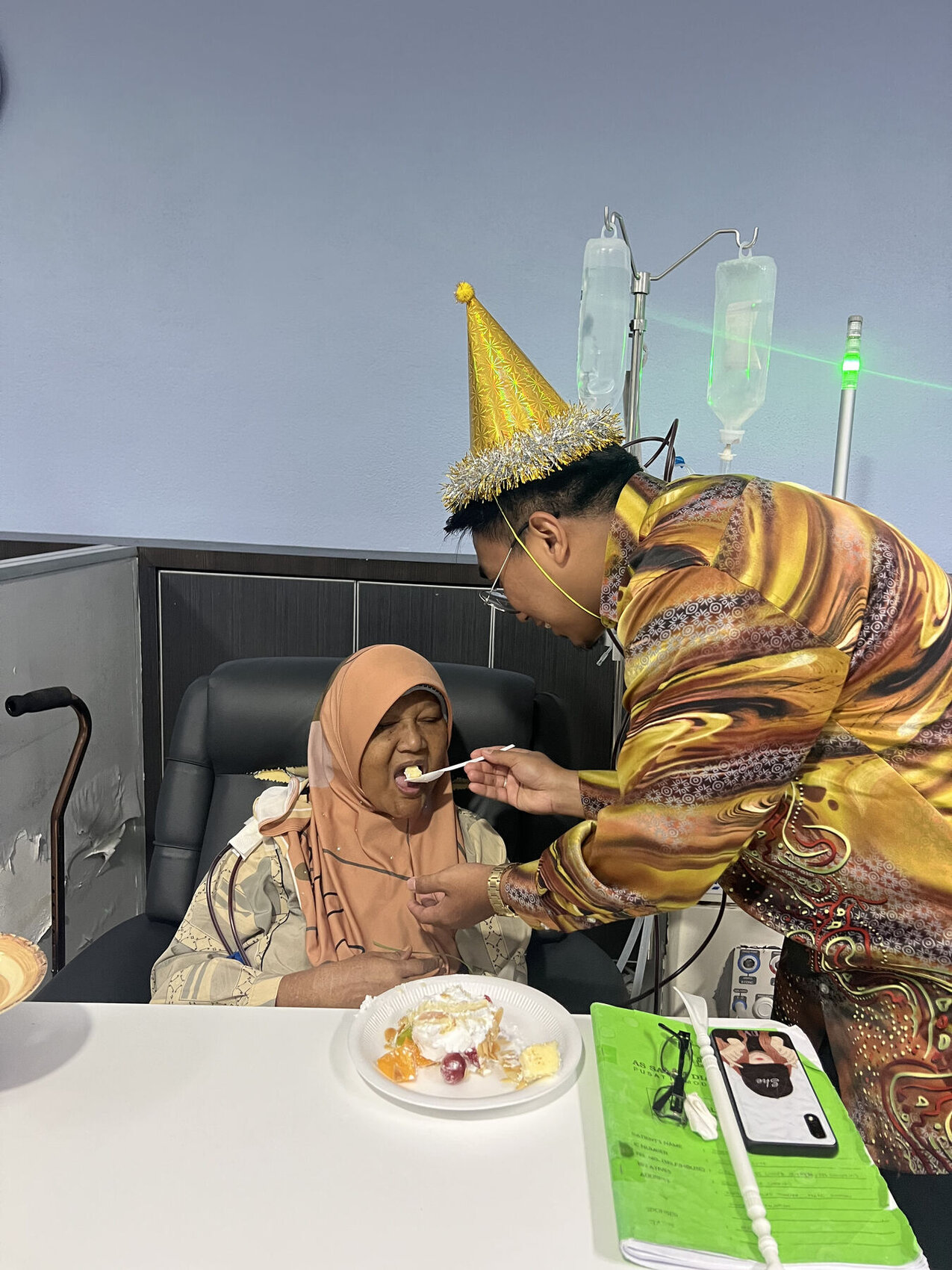A family member feeding a patient during dialysis treatment